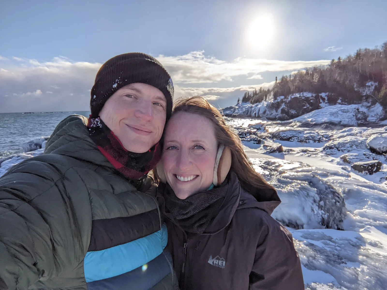 Micah and his wife on a snow-covered Lake Superior shoreline in winter sun